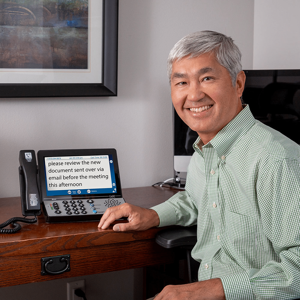 Man with a touch-screen captioned telephone